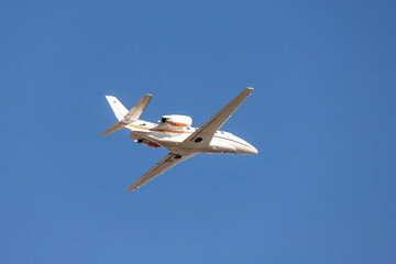 Scenic close bottom view modern luxury expensive white private jet plane dispatching from airport isolated on blue clear sky background. Executive aicraft vip travel concept. Service and maintenance
