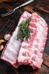 Raw pork spare ribs on a rack with herbs. Wooden background. Top view