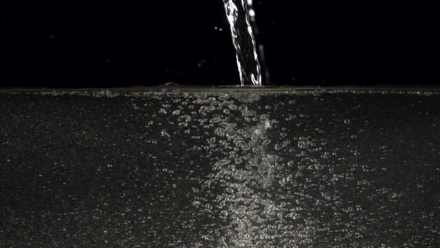 Super slow-motion shot of water splash against black, unfiltered water from plumbing with sediment. Filmed with high speed cinema camera at 1000fps
