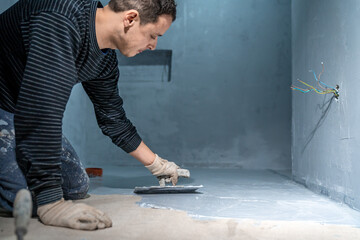 bricklayer works with trowel in room