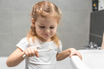 Fototapeta premium Happy toddler brushing teeth in the bath