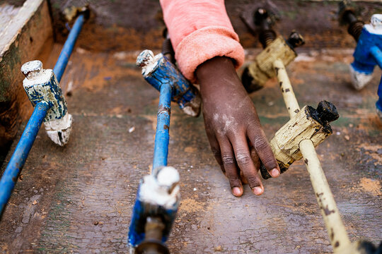 Crop African kid playing mini football on foosball table