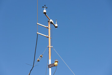 Close-up weather station wind speed direction measurement sensor gauge anemometer against clear blue sky background. Meteorology forecast service equipment at airport runway airfiled