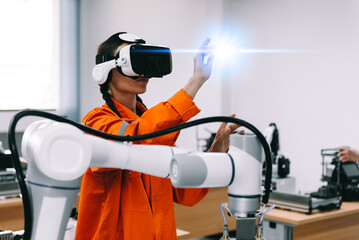 Engineering female wearing VR glasses for simulate control automation robotic welding machines in modern factory lab. Concept of innovation artificial intelligence for industrial revolution.