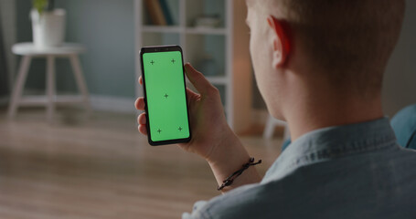 Man using a mobile phone with chroma key green screen, watching a video or having an online conference - technology, communications concept close up