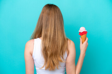 Teenager Russian girl with a cornet ice cream isolated on blue background in back position