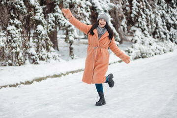 Fototapeta na wymiar Pretty young long-haired woman in pink coat enjoy winter day at snowy park and dancing