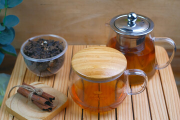 Hot herbal tea drink in glass composition with cinnamon on a wooden pallet