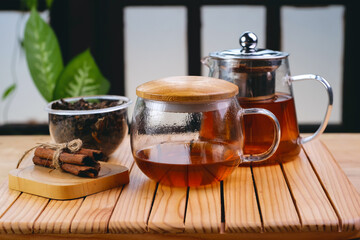 Hot herbal tea drink in glass composition with cinnamon on a wooden pallet