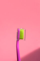 One pink toothbrush on a pink background, close-up. Hard light. Dental care, dental concept.