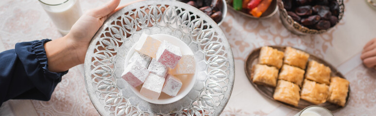 Top view of muslim woman holding plate with turkish delight during suhur and ramadan, banner.