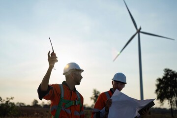 Wind turbine service engineer stand planning for maintenance electricity generator on silhouette