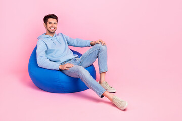 Full body size photo of young chilling soft beanbag guy brunet hair enjoy having rest pause after hard working day isolated on pink color background