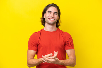 Caucasian handsome man isolated on yellow background laughing