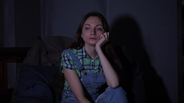 Beautiful woman siting in the dark room and watching TV