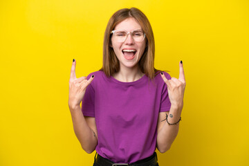 Young English woman isolated on yellow background making horn gesture