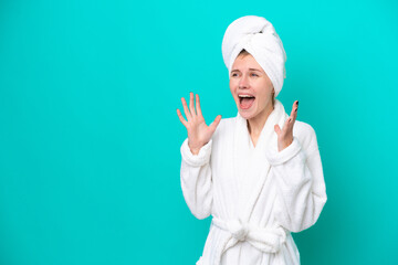 Young woman in a bathrobe isolated on blue background with surprise facial expression