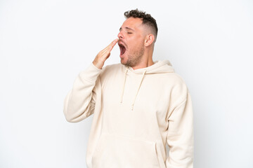 Young caucasian handsome man isolated on white background yawning and covering wide open mouth with hand