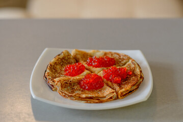 Pancakes. Shrovetide. Pancakes on a white plate. Pancakes with red caviar. Delicious pancakes. Russian pancakes. Delicious dessert. Dinner. Breakfast. Red caviar. Tasty dish