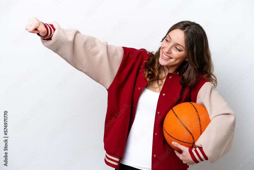 Wall mural Young caucasian woman playing basketball isolated on white background giving a thumbs up gesture