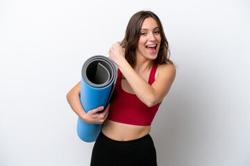 Young sport caucasian woman going to yoga classes while holding a mat isolated on white background celebrating a victory