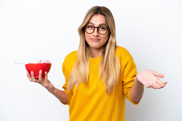 Young Uruguayan woman holding a bowl of cereals isolated on white background making doubts gesture while lifting the shoulders