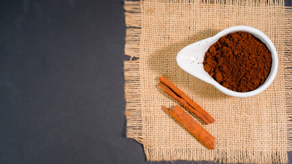 Coffee grounds in a bowl with cinnamon sticks on a burlap napkin, Flat lay, copy space