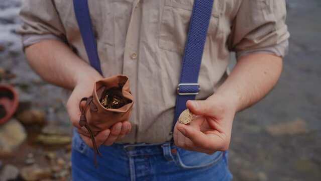 unrecognizable person of a gold digger in the hands of a full bag of gold, gold rush