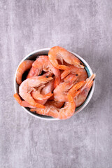 Shrimps in bowl on gray table. Frozen boiled seafood product. Top view