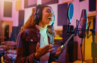 Tablet, music and woman singing in a studio for radio, song production and rehearsal. Creative, voice and a singer making a record, track or recording a musical sound as a professional artist - Powered by Adobe