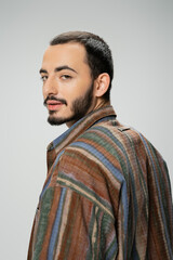 portrait of young bearded man wearing colorful shirt and looking at camera isolated on grey.