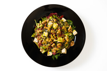 Delicious salad with walnuts, pumpkin seeds and cheese on a black plate