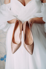 Silver and gold shoes in the hands of the bride 4458.