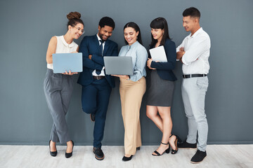 Obraz premium Business, teamwork and laptop on wall background for planning, strategy or online data management. Happy group of employees working on computer, diversity collaboration or research website technology