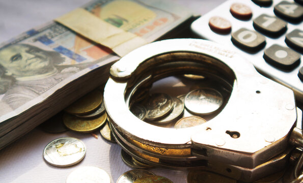 Corruption is the abuse of power for personal gain. It undermines democracy, harms economies, and deprives people of basic services.Police handcuffs and banknote with sepia or film grain image.
