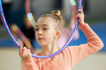 Gracefulness. Little girl, child, rhythmic gymnast training indoors, doing exercise with hoop....