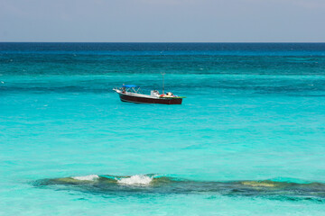 Fishing boat in azure blue ocean water in the Caribbean Sea.