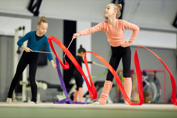 Competition preparation. Little girl, child, rhythmic gymnast training indoor, doing exercise with ribbon. Concept of sportive lifestyle, childhood, education, health, professional sport, championship