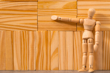 Wooden man figure staying next to wooden wall made fromwooden blocks