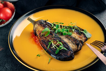 Grilled eggplant cut into pieces on a yellow plate. Vegan aubergine Dish, close up