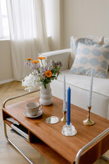 Coffee table in the room with candles and flowers. Stylish interior