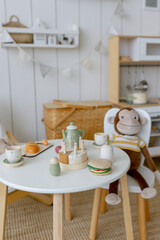 Toy monkey of brown color sits behind a chair in a children's room