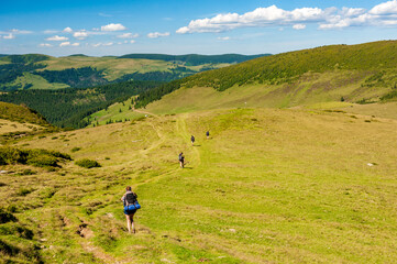 Fototapeta na wymiar Group of trekkers hikers with backpacks descending with veiw of Maramures ridge from Rodna Mountains, Muntii Rodnei National Park, Romania, Romanian Carpathian Mountains, Europe.