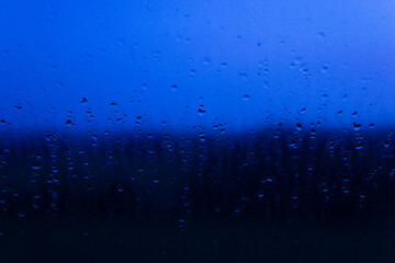 Regen an Fensterscheibe zur blauen Stunde