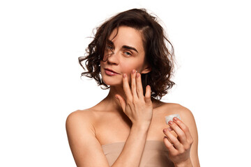 Obraz premium Young beautiful woman taking care after face skin, doing anti-aging procedures with special cosmetical tools over white studio background.