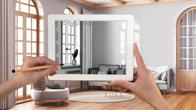 Hands holding and drawing on tablet showing farmhouse living room in boho style details CAD sketch. Real finished interior in the background, architecture design presentation