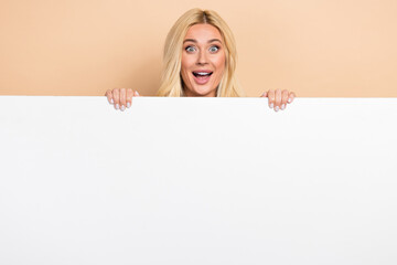 Photo of excited impressed woman holding white gig huge placard empty space isolated beige color background