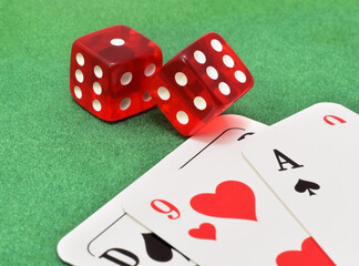 Dice red with white points closed up on green velvet and playing cards