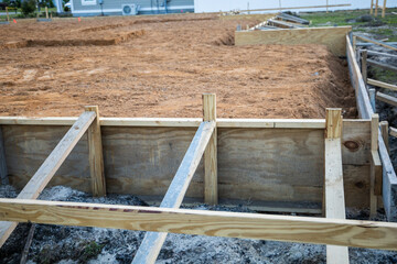 The beginning of a new construction build in a neighborhood with the foundation poured, dirt added and the wood based began