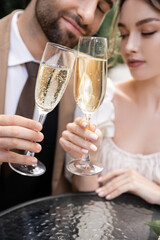 young newlyweds clinking glasses of champagne during wedding celebration.